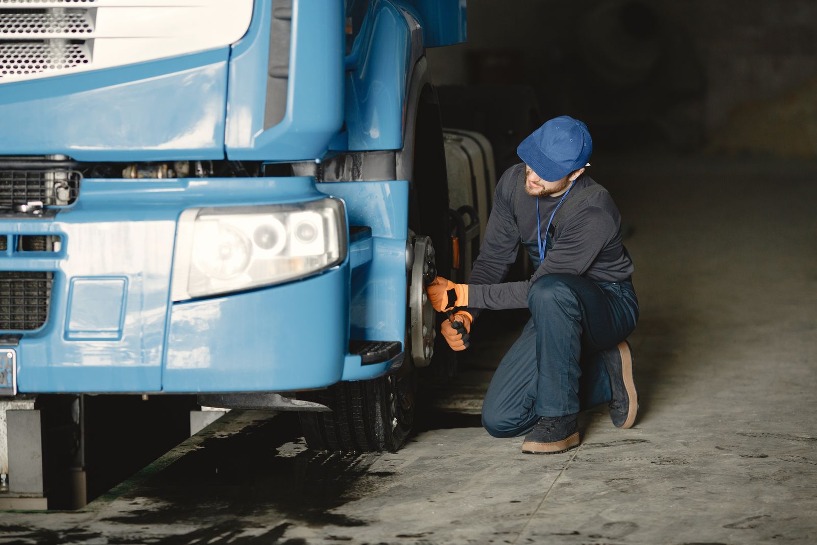 Mechanic tightening the wheel nuts on a truck’s front wheel